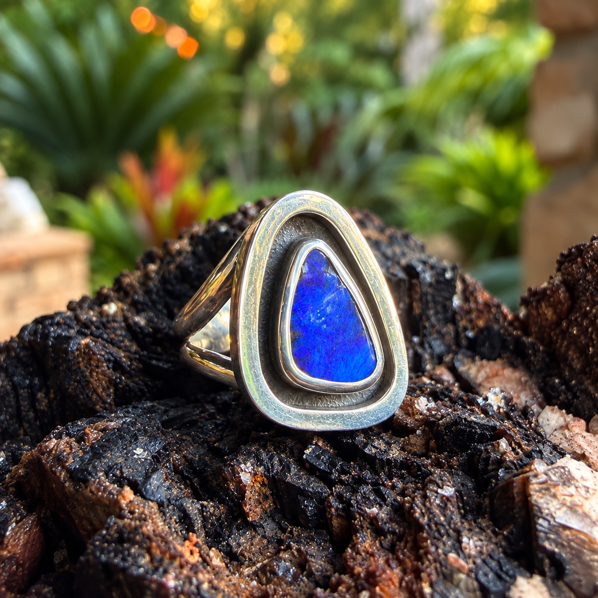 Angled view of Cobalt Cove showing the blue boulder opal, polished silver border, and split shank.

