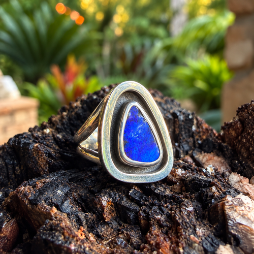 Angled view of Cobalt Cove showing the blue boulder opal, polished silver border, and split shank.

