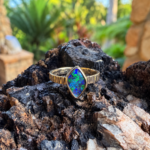 front view of Prism Tide’s angular blue-green Boulder opal in a yellow gold bezel.
