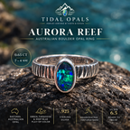 Aurora Reef Australian boulder opal ring on dark coastal rock, with a green, turquoise and blue oval stone and handcrafted textured silver band.