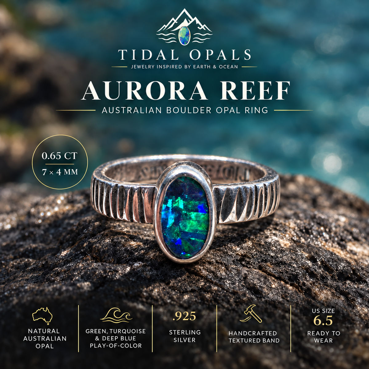 Aurora Reef Australian boulder opal ring on dark coastal rock, with a green, turquoise and blue oval stone and handcrafted textured silver band.