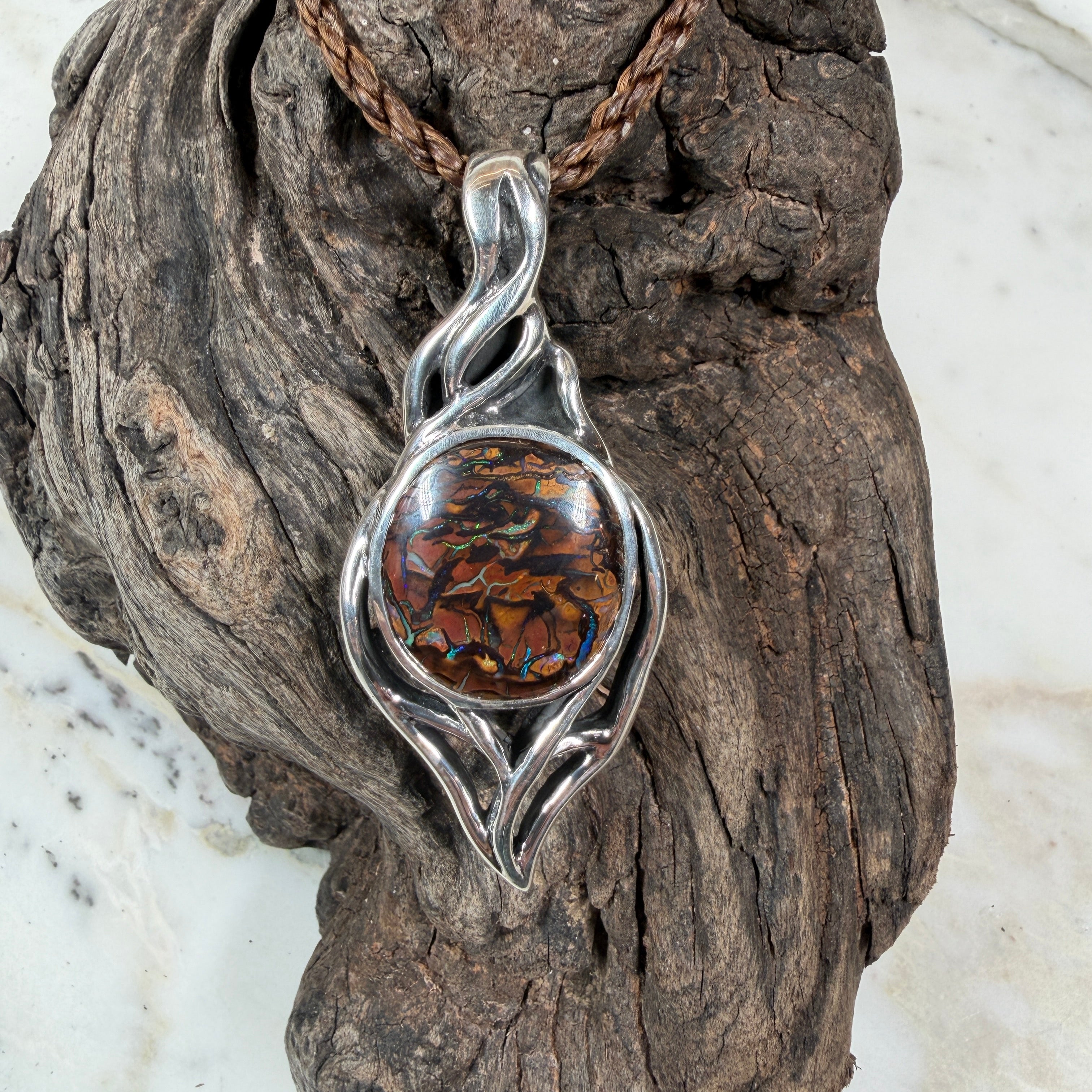  Australian Boulder Opal with blue and green fire surrounded by sculptural flowing silver rails.
