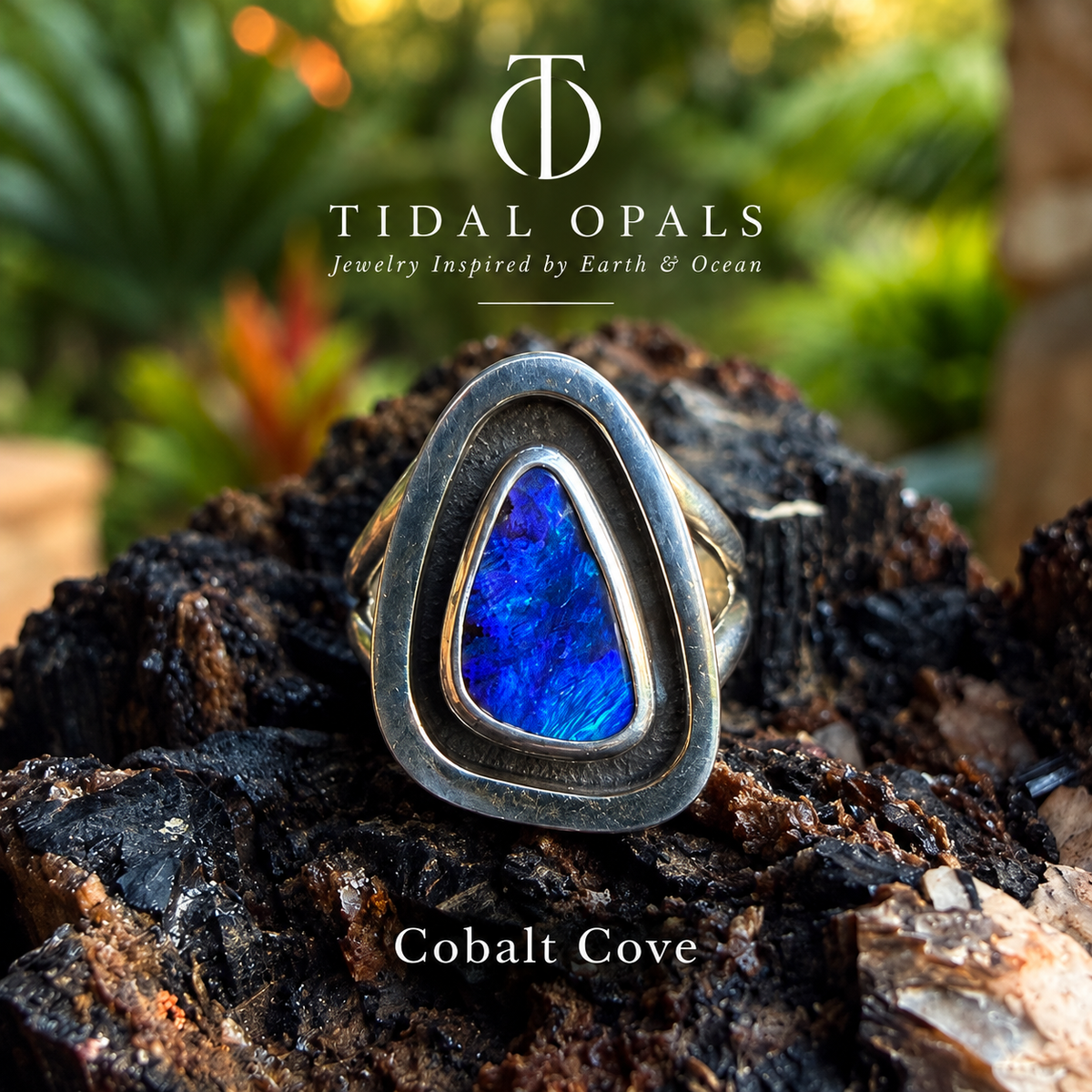 Cobalt Cove deep blue boulder opal ring in a polished sterling silver shadowbox setting with a dark oxidized interior, resting on textured wood.

