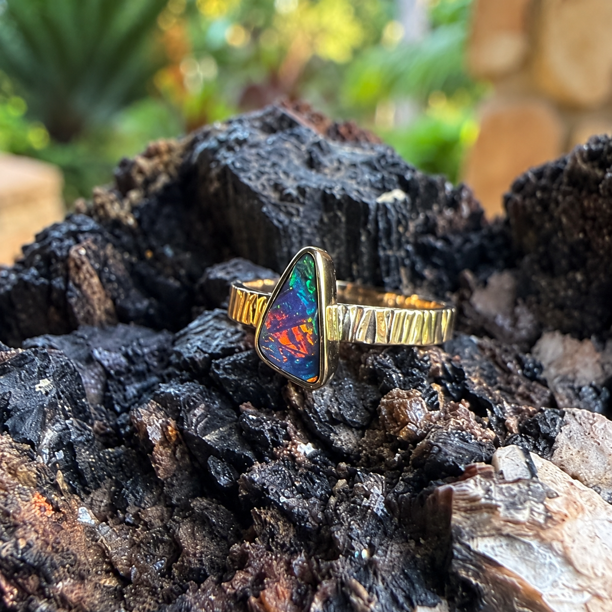  Angled view of Solar Crest showing its gold bezel, textured band, and warm flashes in the opal.
