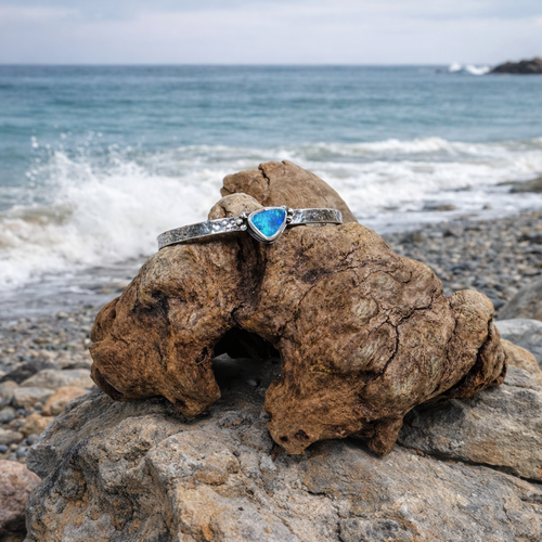 .925 Sterling Silver cuff with blue and green  Australian Boulder Opal stone near the ocean.