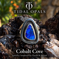 Cobalt Cove deep blue boulder opal ring in a polished sterling silver shadowbox setting with a dark oxidized interior, resting on textured wood.