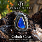 Cobalt Cove deep blue boulder opal ring in a polished sterling silver shadowbox setting with a dark oxidized interior, resting on textured wood.