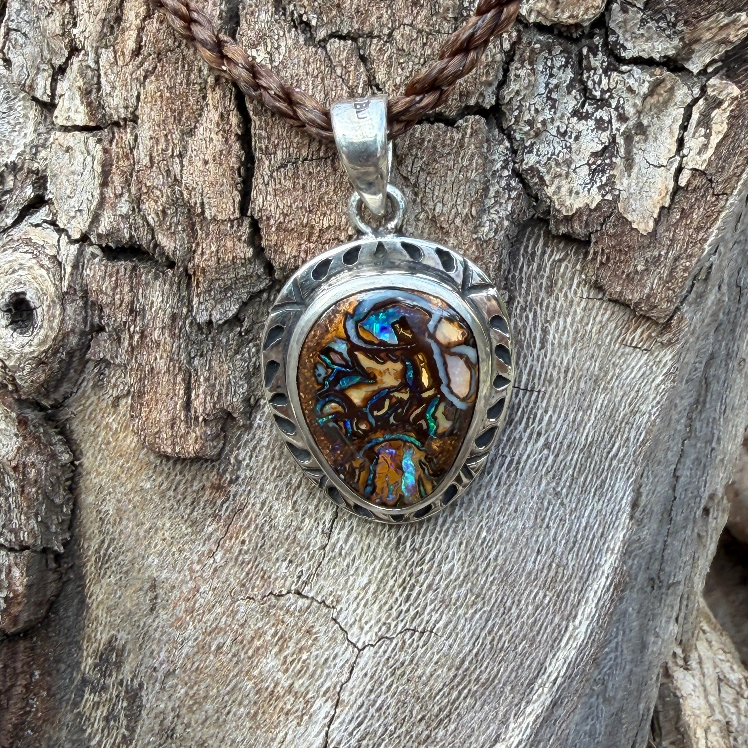 Elegant sterling silver pendant with a genuine Australian Boulder Opal displaying brilliant electric blue, aqua green, and turquoise hues.