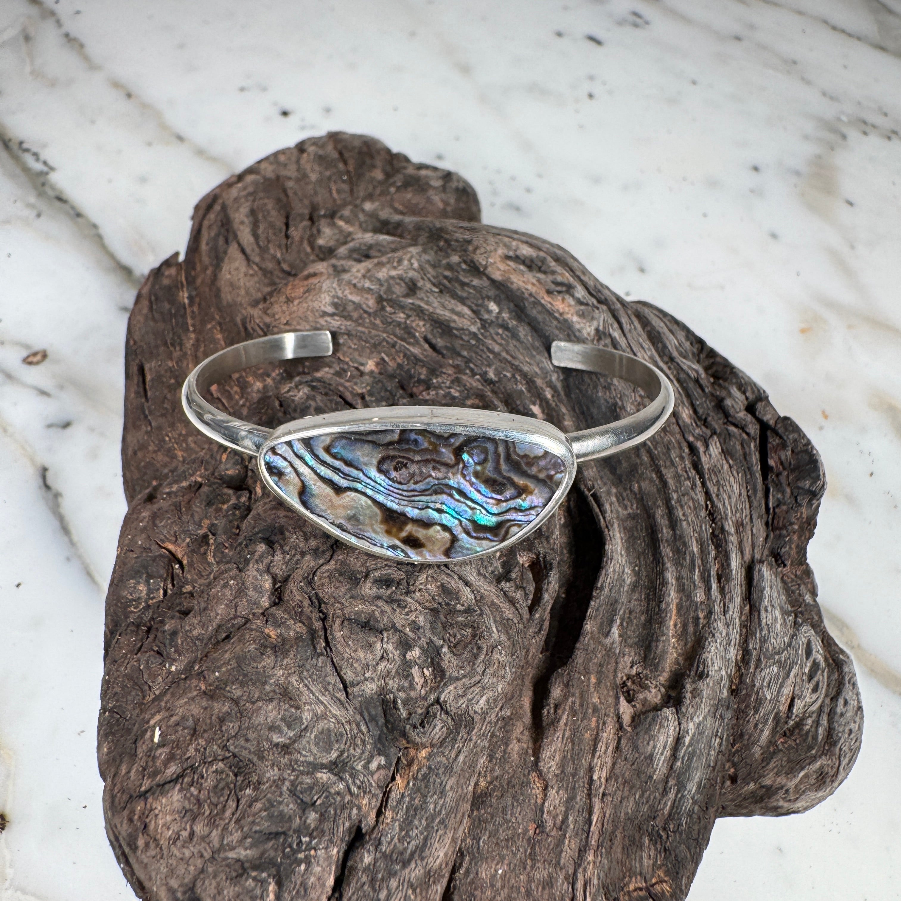 Discover the raw beauty of the ocean with our Babylon Abalone Shell Cuff, a one-of-a-kind piece 