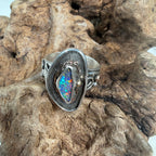 Reef Current handcrafted Australian Boulder Opal ring in .925 sterling silver with a 14K gold rope bezel and gold accents displayed on weathered driftwood.