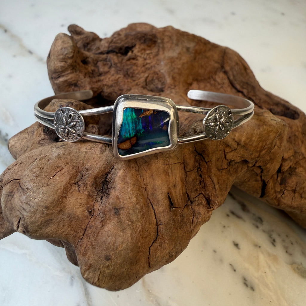 Capture the beauty of shifting light with the Aurora Ridge Boulder Opal Cuff Bracelet, a one-of-a-kind handcrafted piece inspired by the colors of the northern sky. 