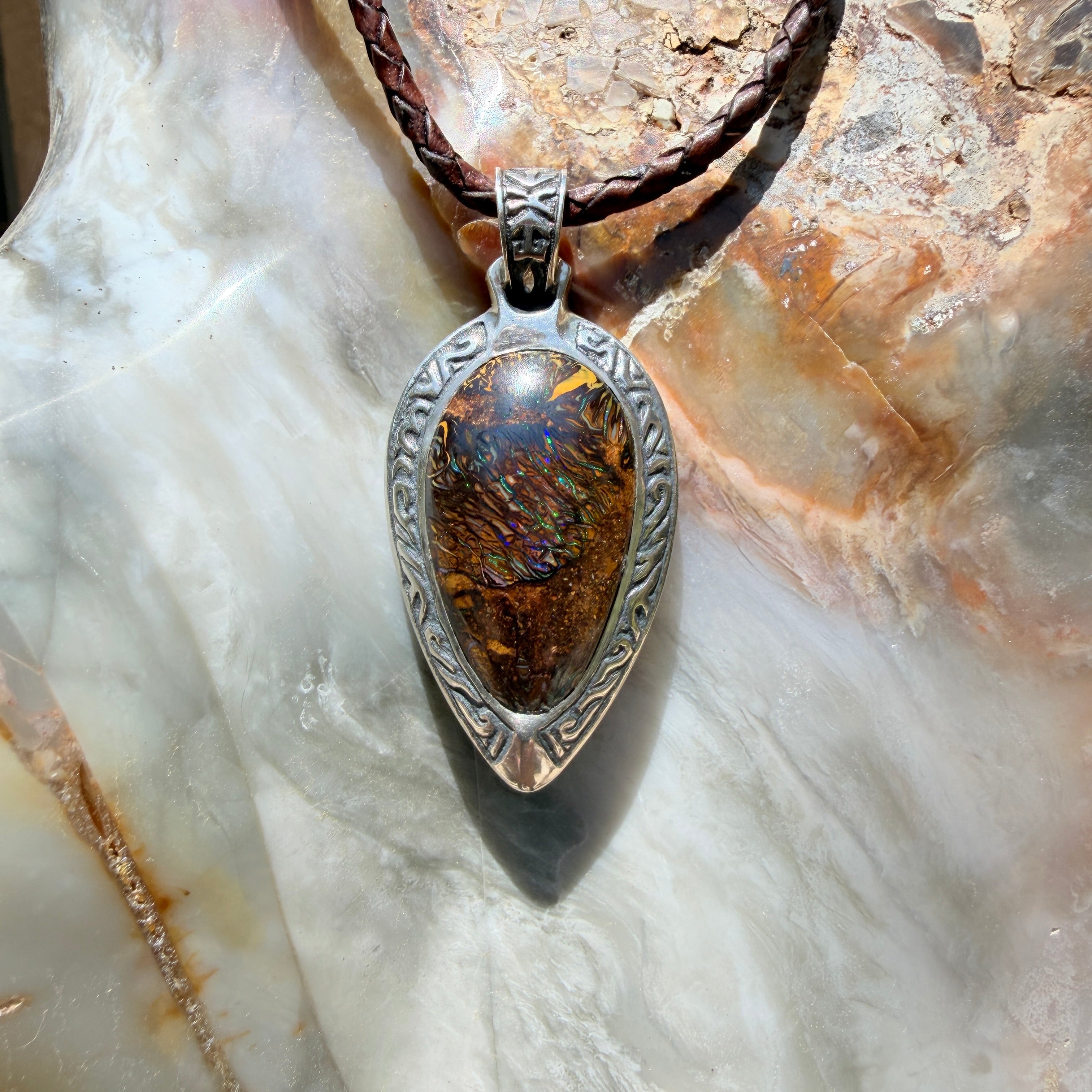 Ancient Tide one-of-a-kind Australian Boulder Opal pendant handcrafted in solid .950 silver by TIDAL OPALS, featuring a natural 31 x 18 mm boulder opal with blue, teal, green, violet, and gold play-of-color, hand-engraved details, and an intricate hand-pierced backplate.