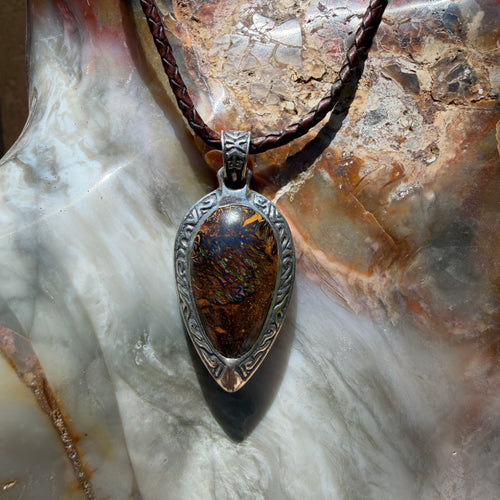 Ancient Tide one-of-a-kind Australian Boulder Opal pendant handcrafted in solid .950 silver by TIDAL OPALS, featuring a natural 31 x 18 mm boulder opal with blue, teal, green, violet, and gold play-of-color, hand-engraved details, and an intricate hand-pierced backplate.