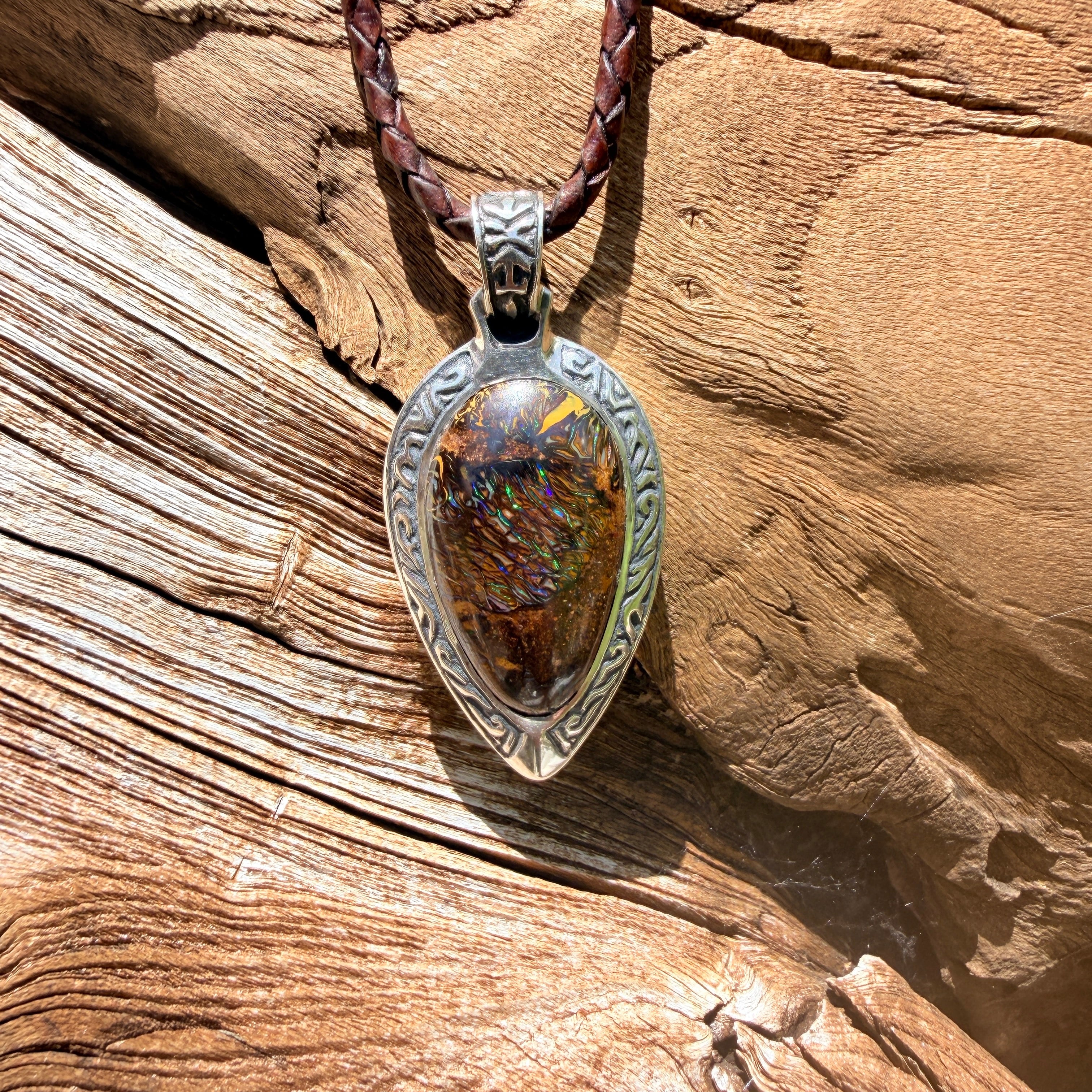Ancient Tide one-of-a-kind Australian Boulder Opal pendant handcrafted in solid .950 silver by TIDAL OPALS, featuring a natural 31 x 18 mm boulder opal with blue, teal, green, violet, and gold play-of-color, hand-engraved details, and an intricate hand-pierced backplate.