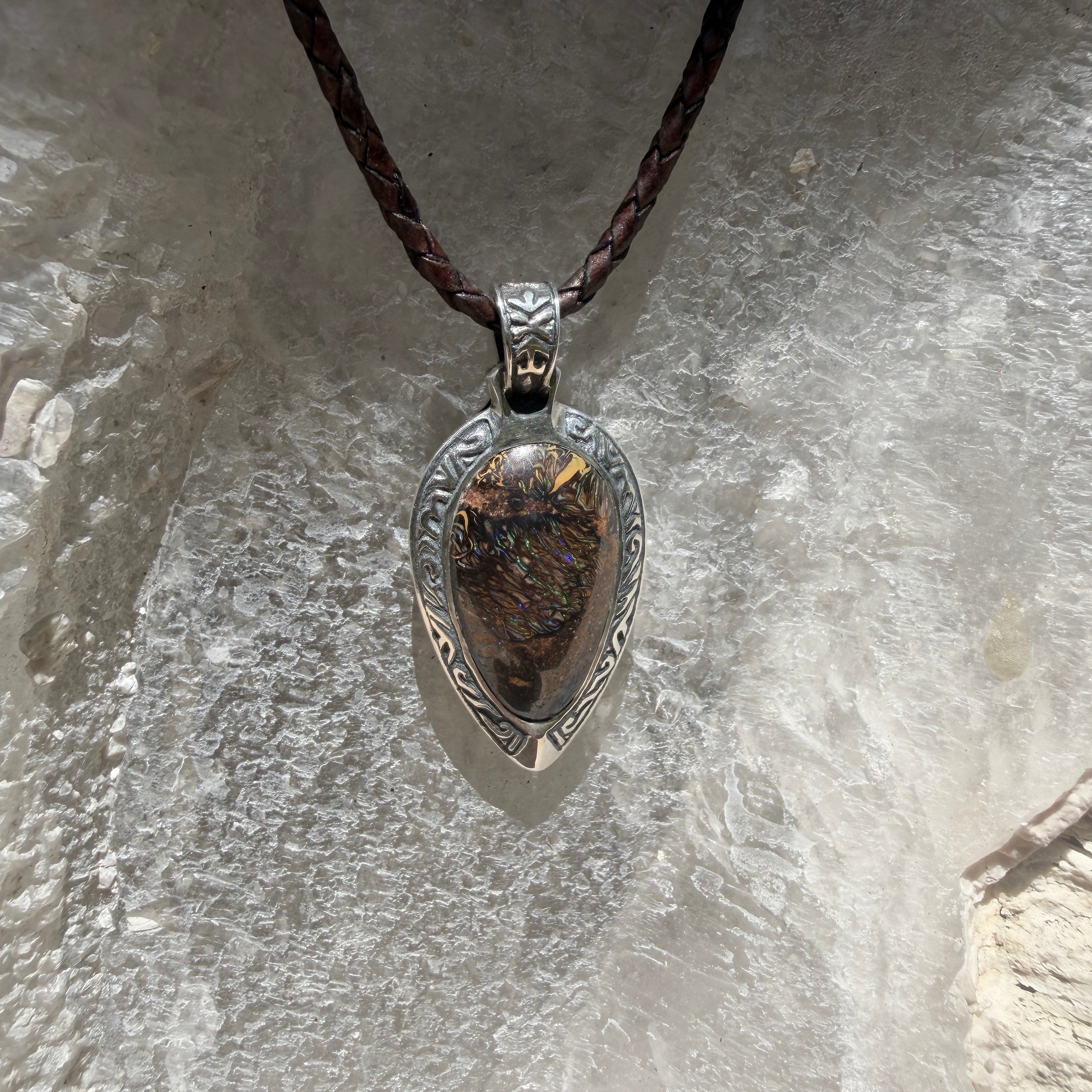 Ancient Tide one-of-a-kind Australian Boulder Opal pendant handcrafted in solid .950 silver by TIDAL OPALS, featuring a natural 31 x 18 mm boulder opal with blue, teal, green, violet, and gold play-of-color, hand-engraved details, and an intricate hand-pierced backplate.