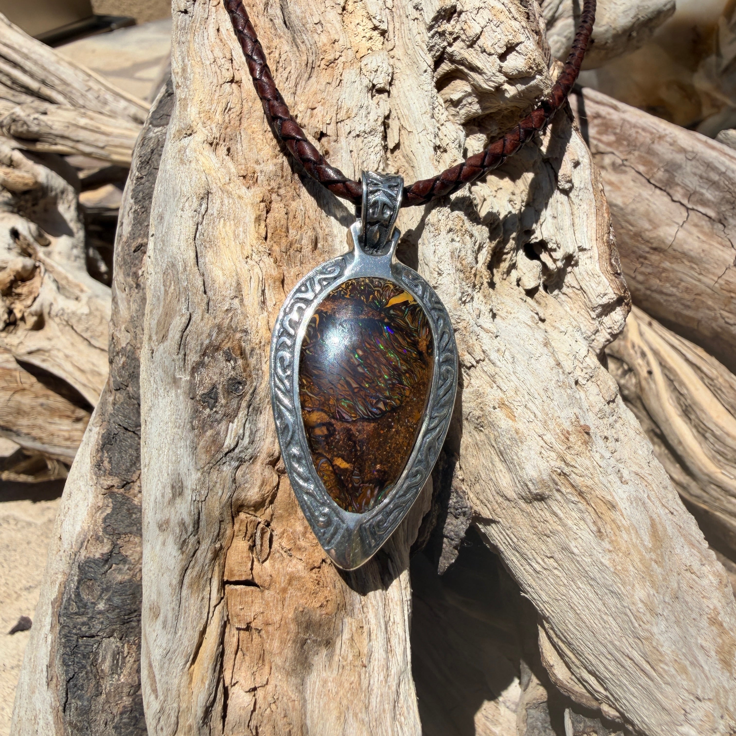 Ancient Tide one-of-a-kind Australian Boulder Opal pendant handcrafted in solid .950 silver by TIDAL OPALS, featuring a natural 31 x 18 mm boulder opal with blue, teal, green, violet, and gold play-of-color, hand-engraved details, and an intricate hand-pierced backplate.