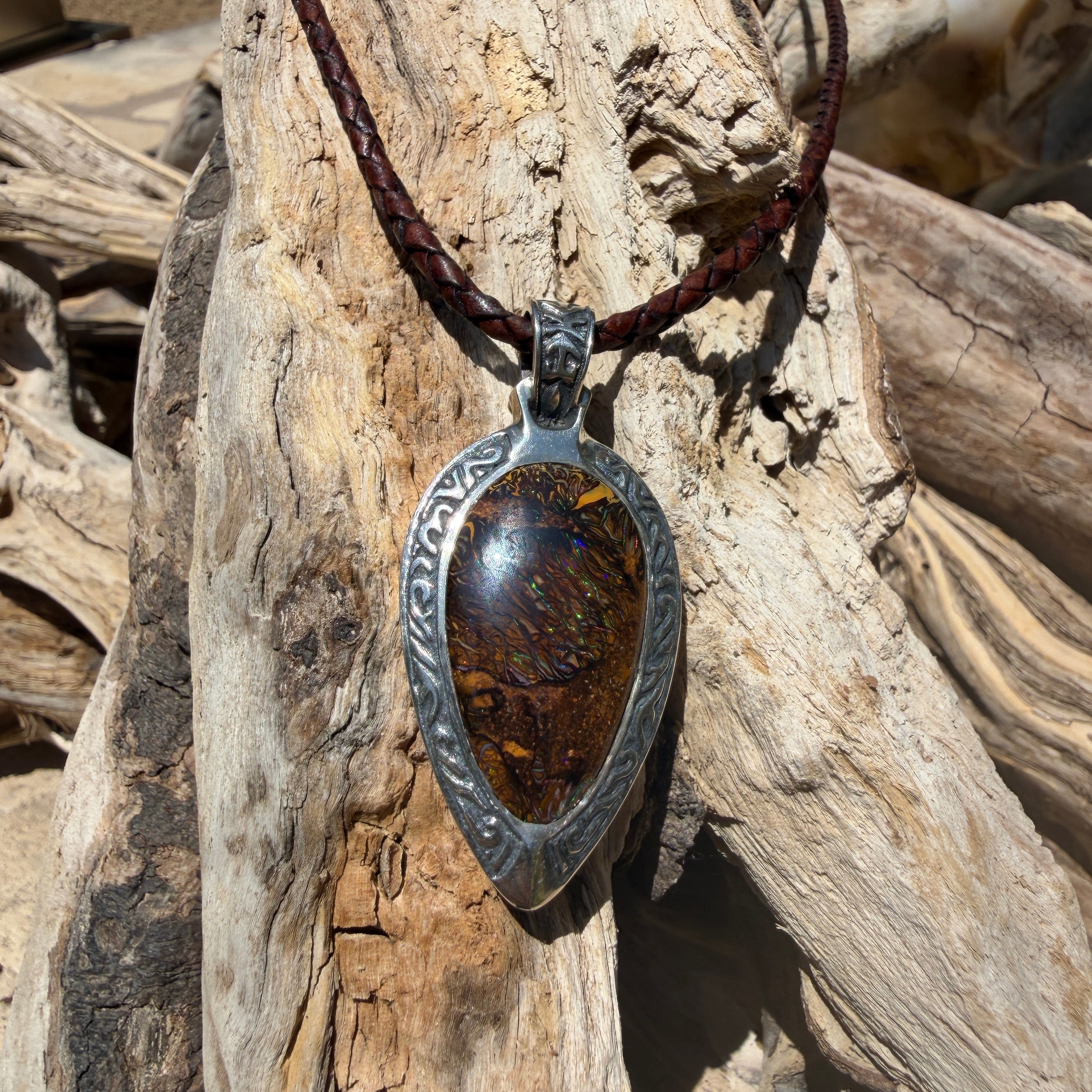 Ancient Tide one-of-a-kind Australian Boulder Opal pendant handcrafted in solid .950 silver by TIDAL OPALS, featuring a natural 31 x 18 mm boulder opal with blue, teal, green, violet, and gold play-of-color, hand-engraved details, and an intricate hand-pierced backplate.
