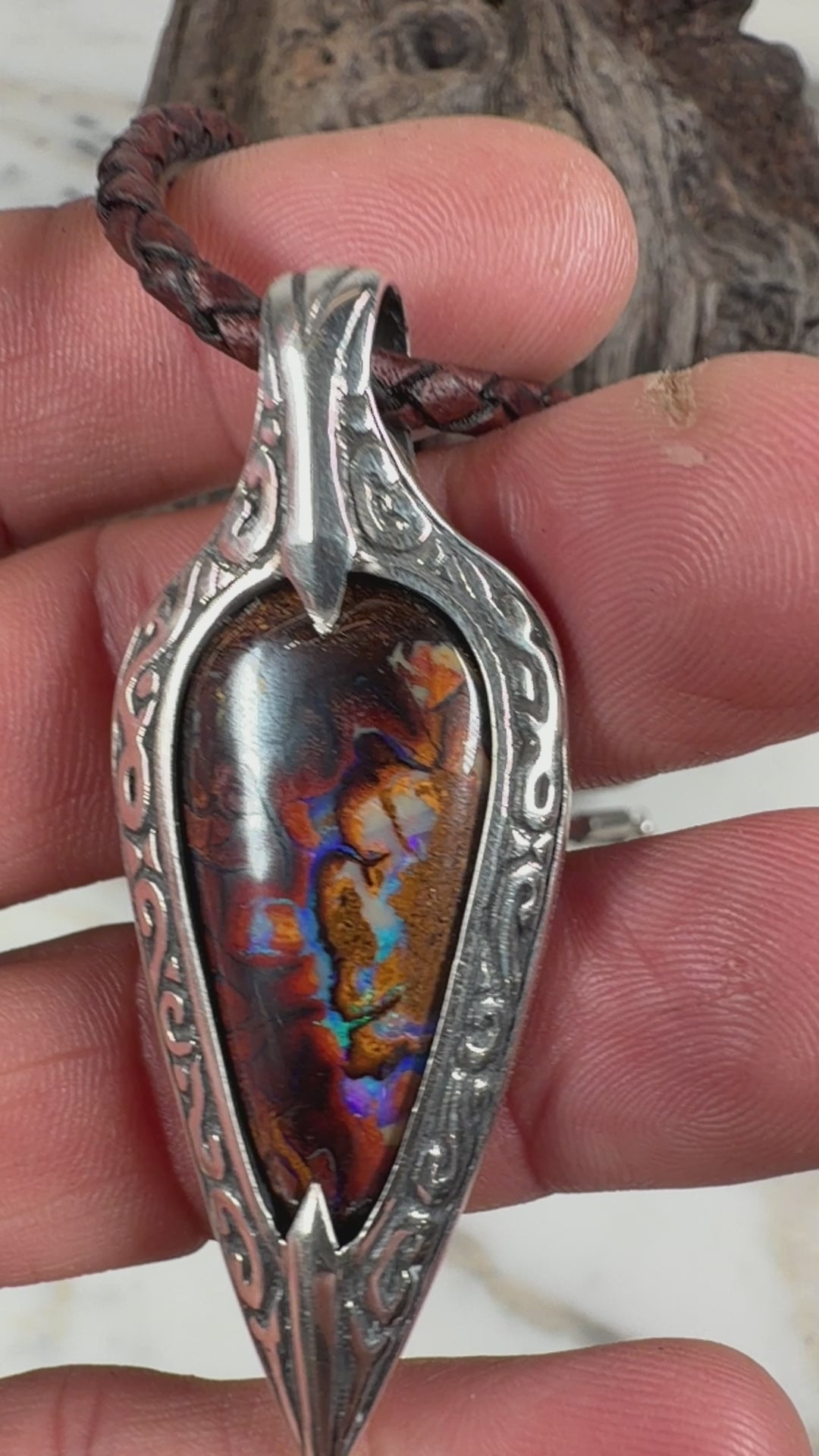 Angled view of the Ember Relic natural boulder opal pendant in a hand-fabricated spear-shaped sterling silver setting.