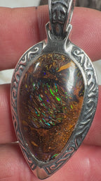 Ancient Tide one-of-a-kind Australian Boulder Opal pendant handcrafted in solid .950 silver by TIDAL OPALS, featuring a natural 31 x 18 mm boulder opal with blue, teal, green, violet, and gold play-of-color, hand-engraved details, and an intricate hand-pierced backplate.
