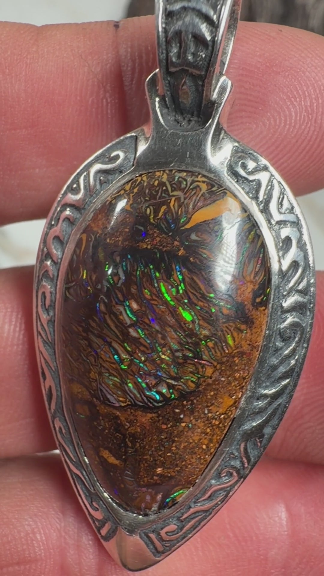 Ancient Tide one-of-a-kind Australian Boulder Opal pendant handcrafted in solid .950 silver by TIDAL OPALS, featuring a natural 31 x 18 mm boulder opal with blue, teal, green, violet, and gold play-of-color, hand-engraved details, and an intricate hand-pierced backplate.