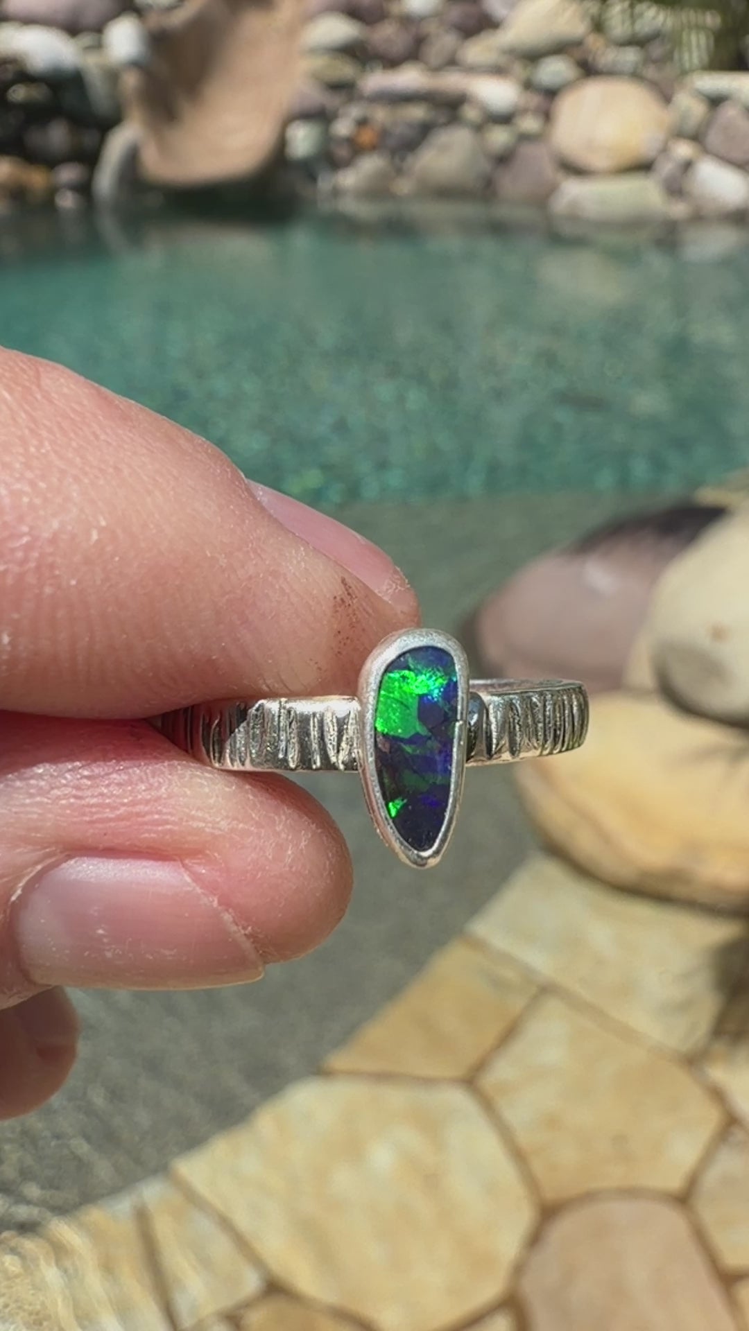 Australian Boulder Opal ring with bright green and blue color in a textured sterling silver band.