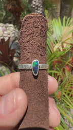 Boulder Opal ring showing bright green flashes over a dark blue stone with a sterling silver band.