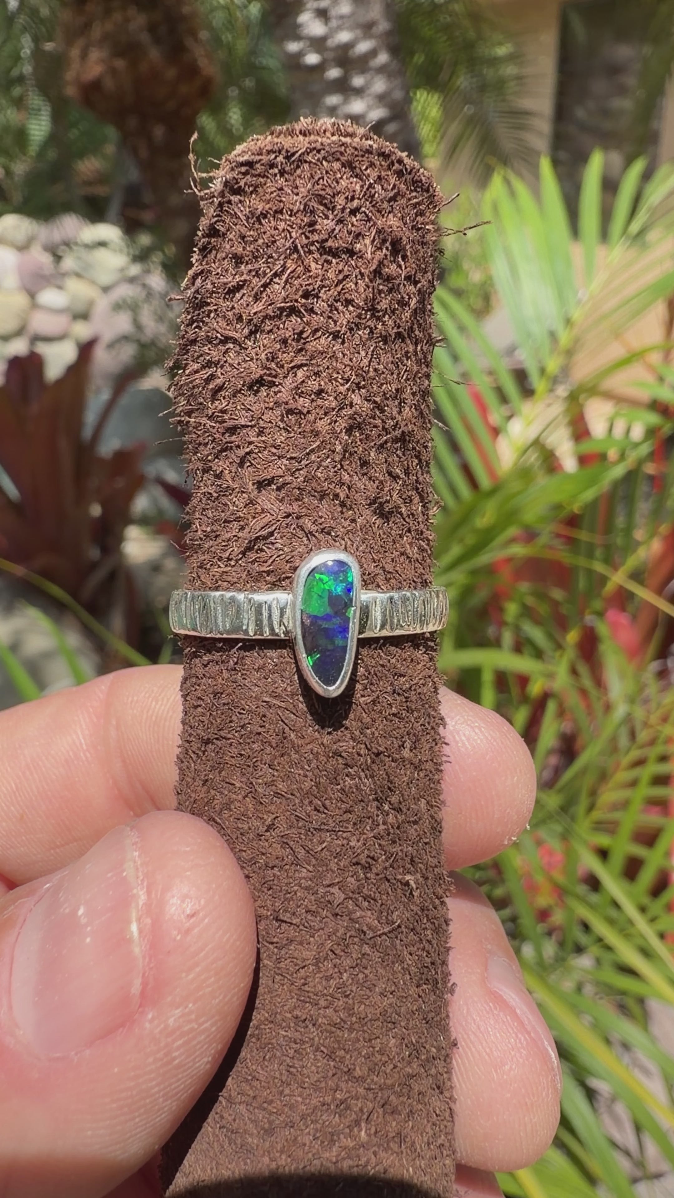 Boulder Opal ring showing bright green flashes over a dark blue stone with a sterling silver band.