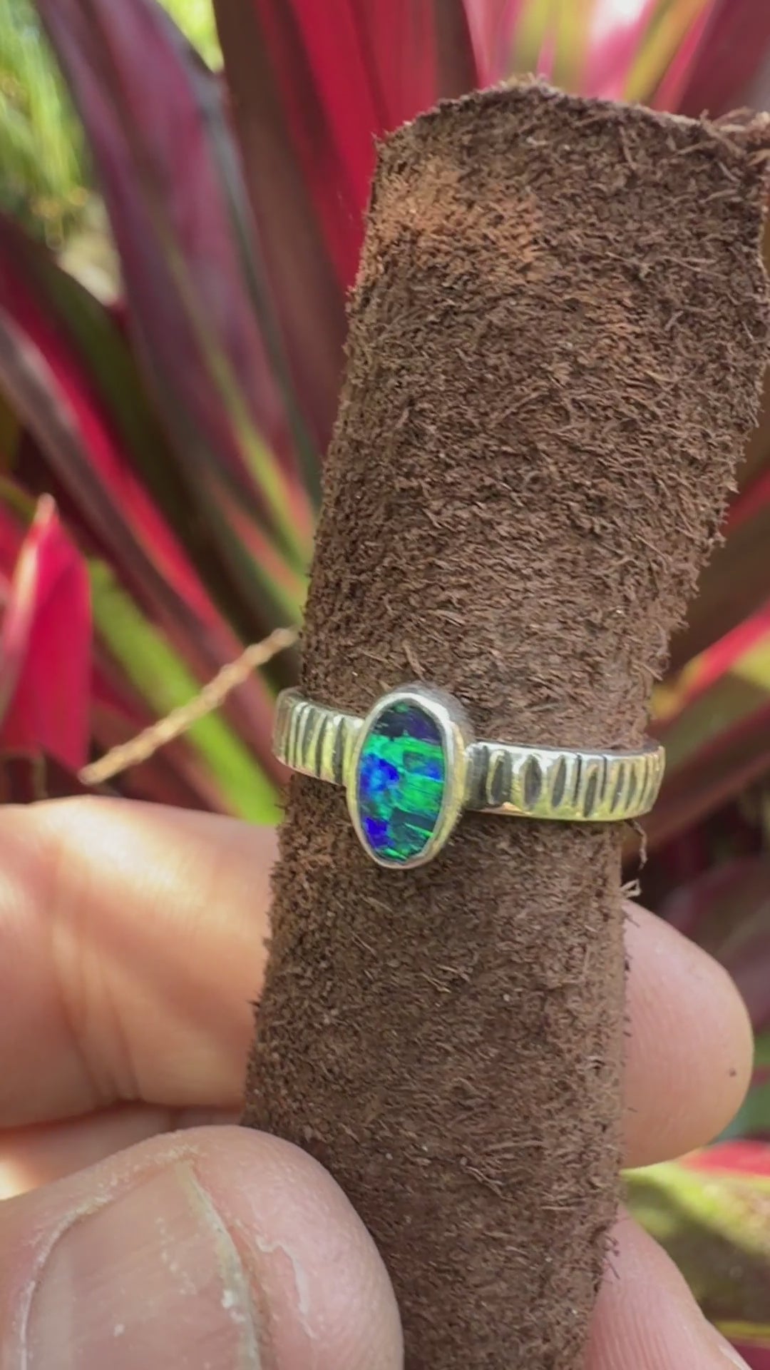 Australian boulder opal ring with bright green and turquoise color play set in a textured silver band.